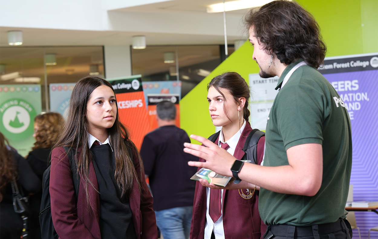 school students talking to college student at an open event