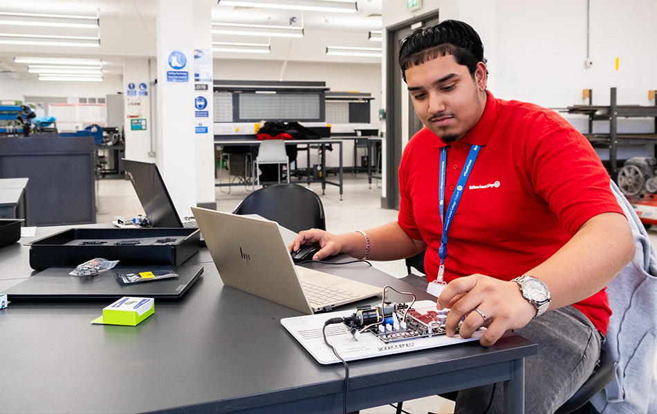 Engineering student with an electronics board and a laptop