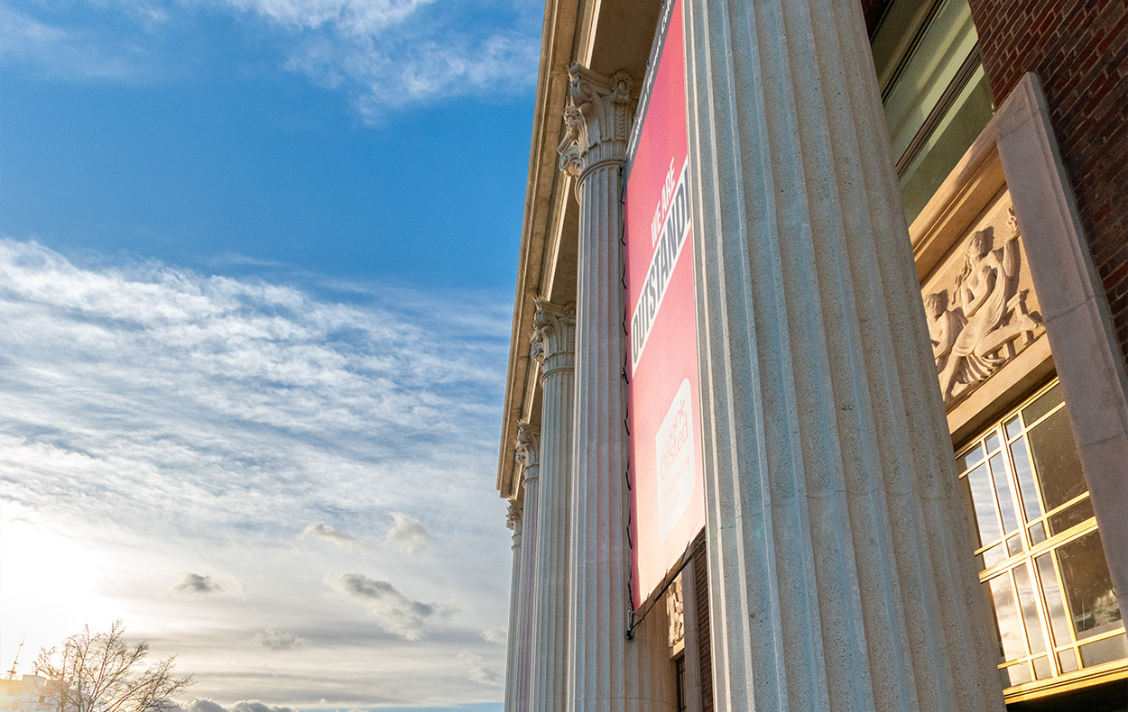 Waltham Forest College pillars against a blue and cloudy sky