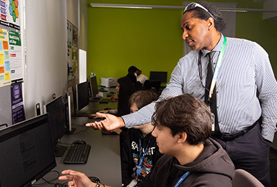 Teacher assisting student at a computer