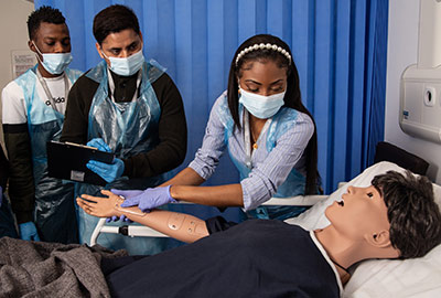 Healthcare students practicing treatment on a training dummy