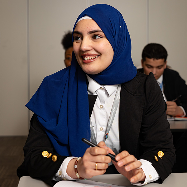 Lady sitting at desk smiling holding a pen