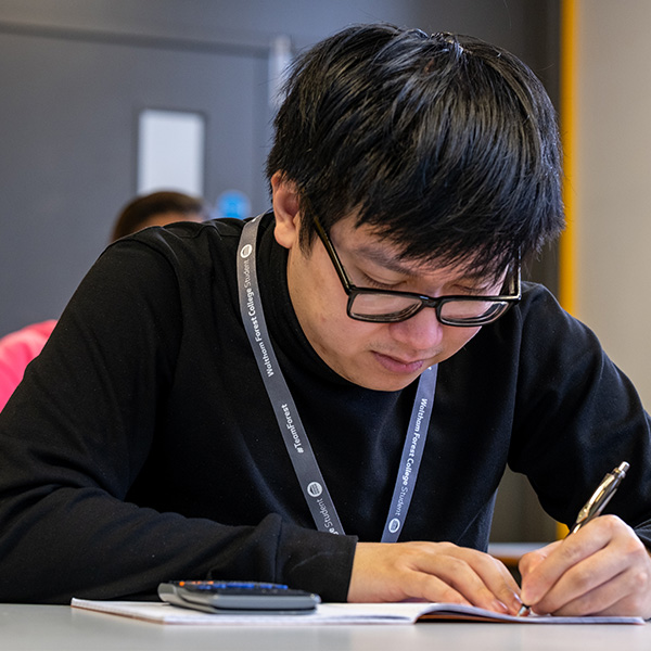 Student studying with a calculator and workbook